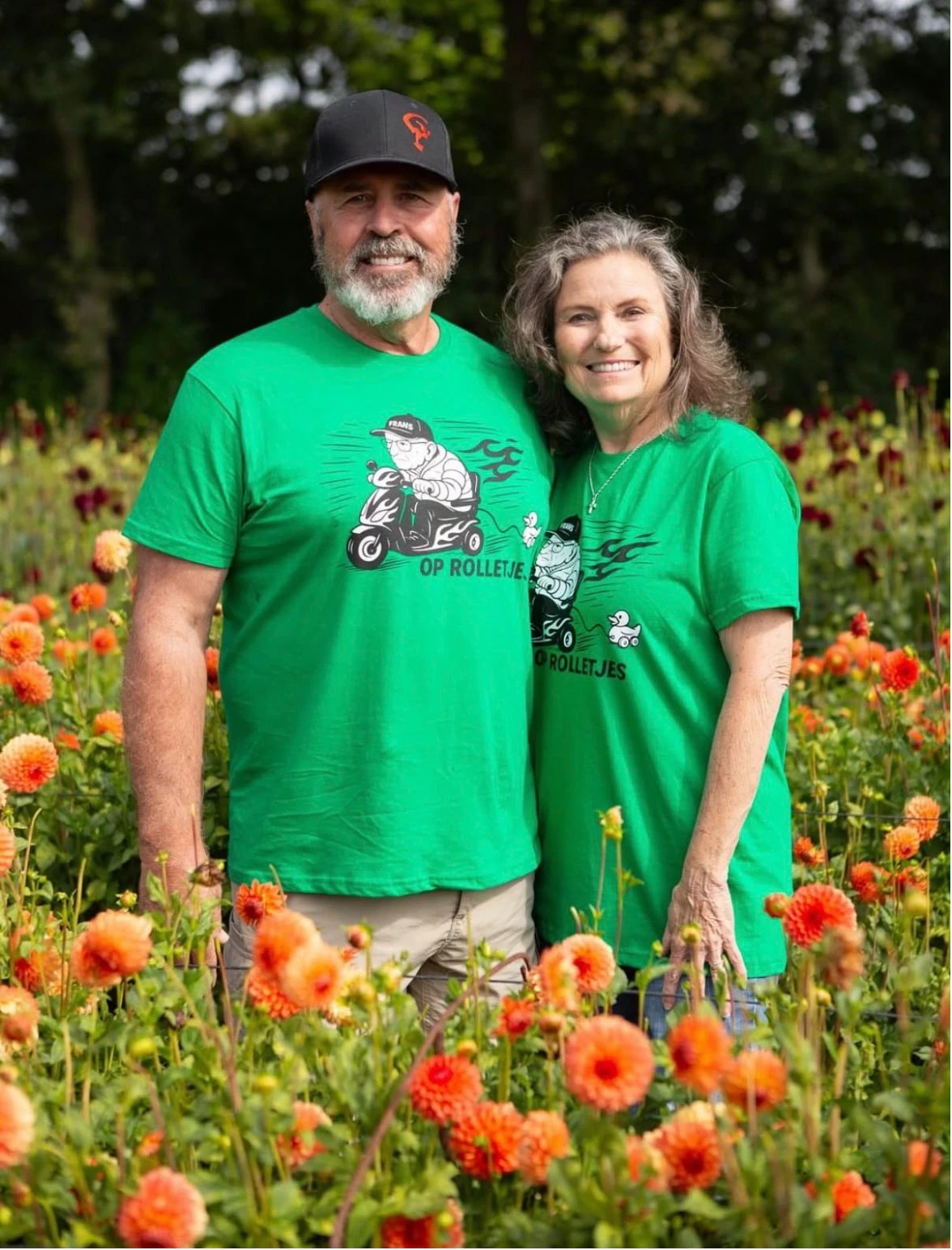 Twee mensen in het groene Op Rolletjes-shirt tussen de dahlia's